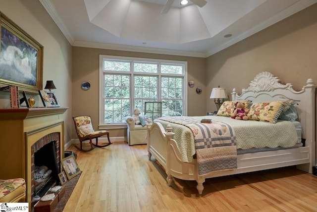 bedroom with light hardwood / wood-style floors, a tray ceiling, and multiple windows