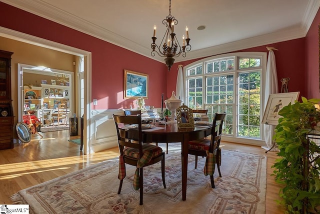 dining room with a notable chandelier, light hardwood / wood-style flooring, and crown molding