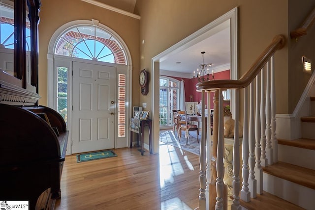 entryway featuring crown molding, a notable chandelier, and light hardwood / wood-style flooring