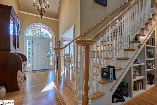 foyer with light hardwood / wood-style floors, ornamental molding, and a chandelier