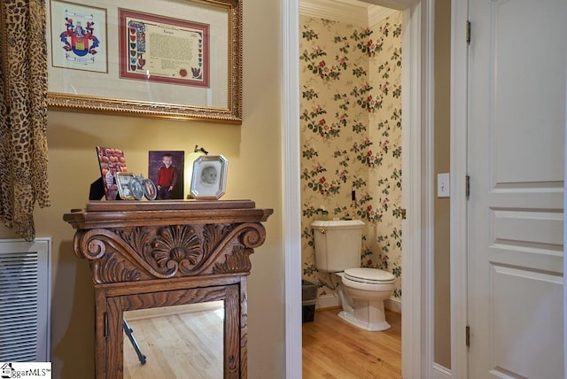 bathroom featuring ornamental molding, toilet, and wood-type flooring