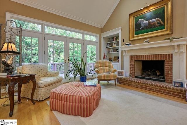 sitting room featuring built in features, a brick fireplace, crown molding, light hardwood / wood-style flooring, and high vaulted ceiling