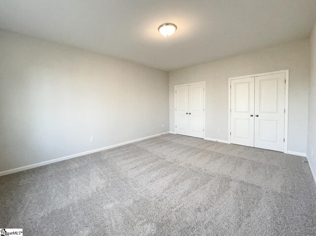 unfurnished bedroom with two closets and carpet floors