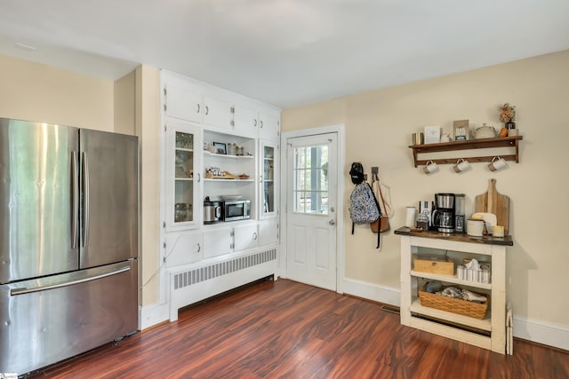 interior space with white cabinetry, stainless steel appliances, radiator, and dark wood-type flooring