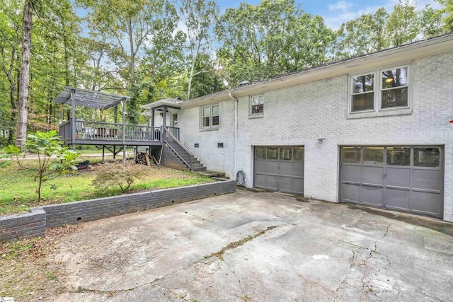 back of property featuring a garage, a wooden deck, and a pergola