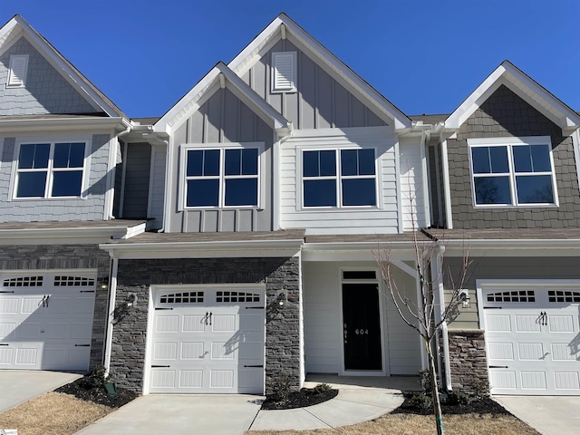 view of property with stone siding, an attached garage, board and batten siding, and driveway