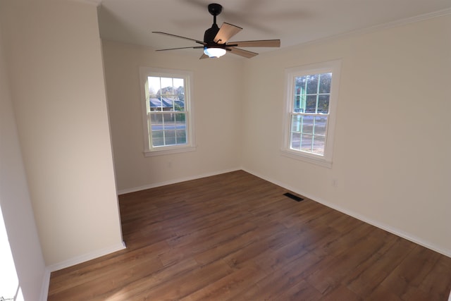 empty room featuring crown molding, a healthy amount of sunlight, and dark hardwood / wood-style floors