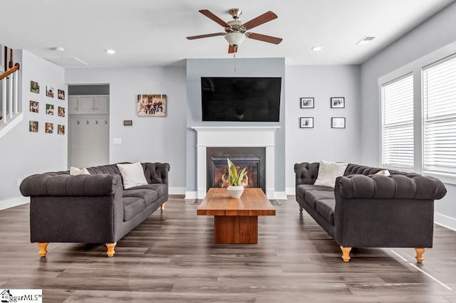 living room featuring dark wood-type flooring and ceiling fan