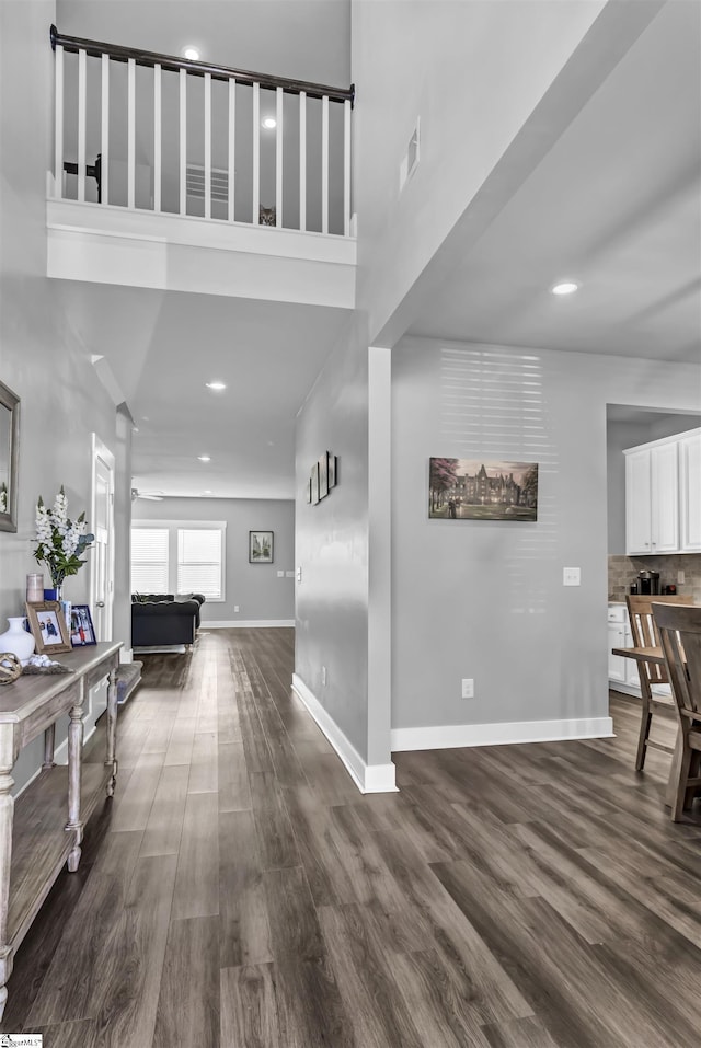 interior space featuring a towering ceiling and dark hardwood / wood-style flooring