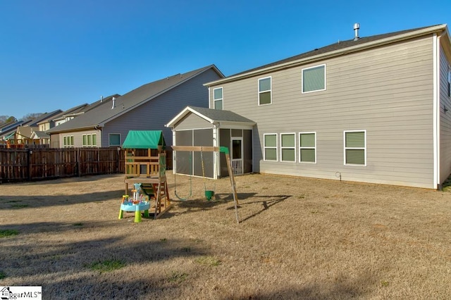 rear view of house featuring a yard and a playground