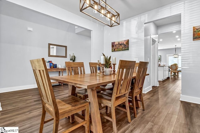 dining area with a notable chandelier and dark hardwood / wood-style flooring