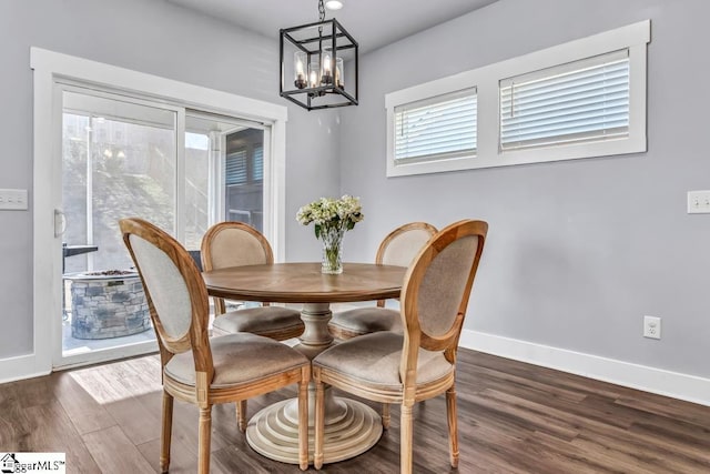 dining space with dark hardwood / wood-style floors and a notable chandelier