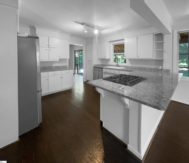 kitchen with kitchen peninsula, stainless steel appliances, a breakfast bar, white cabinets, and sink