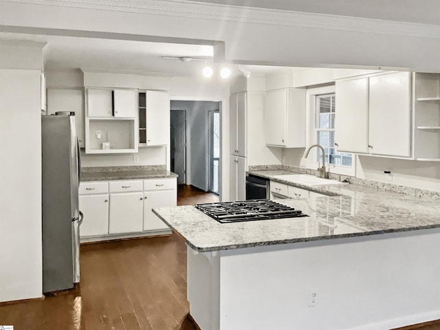 kitchen with appliances with stainless steel finishes, kitchen peninsula, white cabinets, and sink