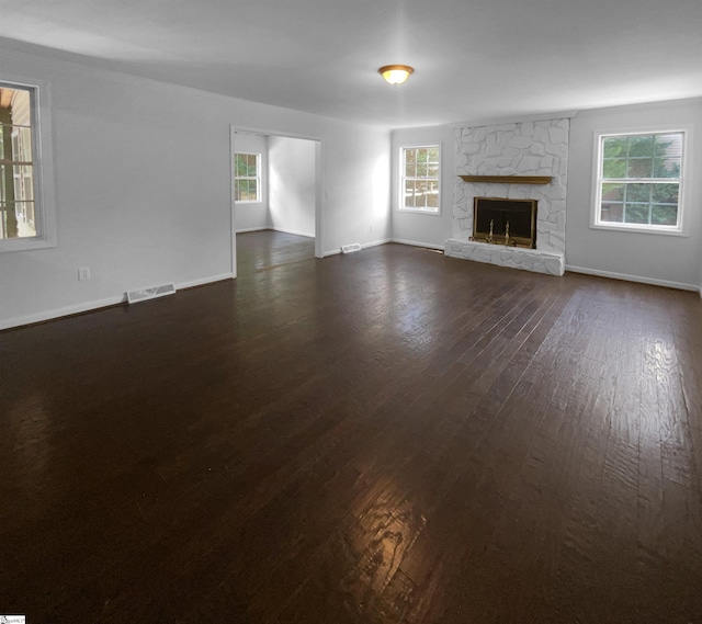 unfurnished living room with dark hardwood / wood-style floors and a stone fireplace