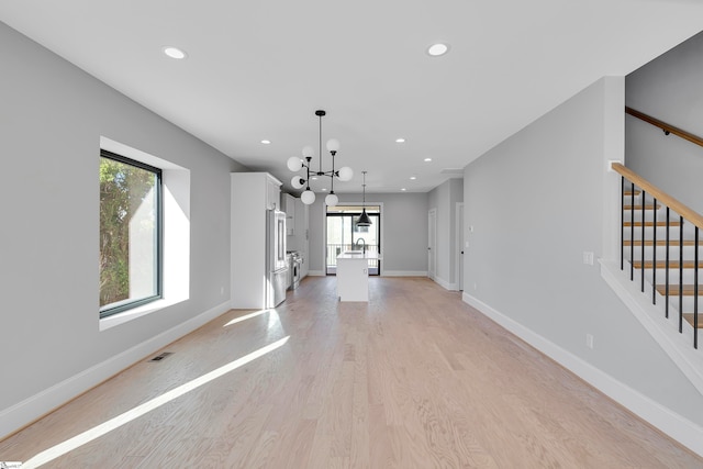 unfurnished dining area featuring plenty of natural light, light hardwood / wood-style floors, and a chandelier