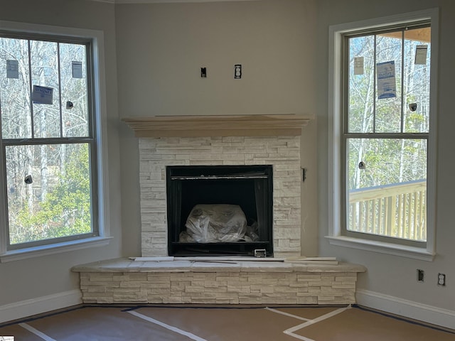 interior details featuring a stone fireplace and baseboards