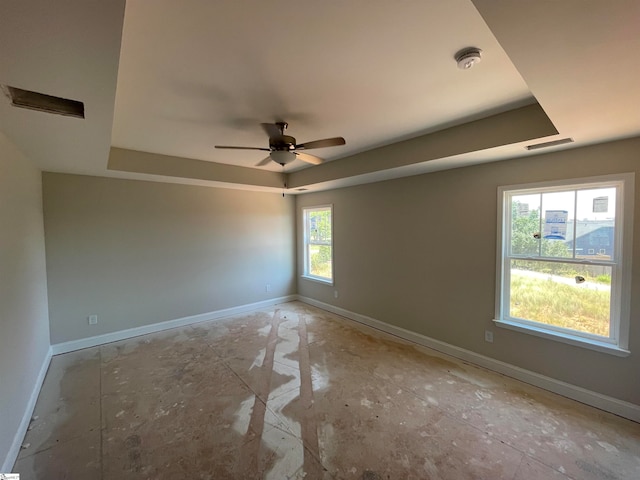 spare room featuring a raised ceiling, a wealth of natural light, and ceiling fan