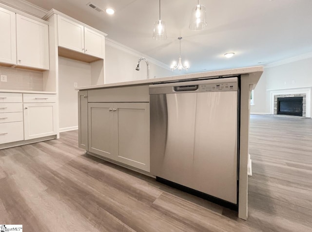 kitchen featuring pendant lighting, tasteful backsplash, dishwasher, white cabinets, and light wood-type flooring