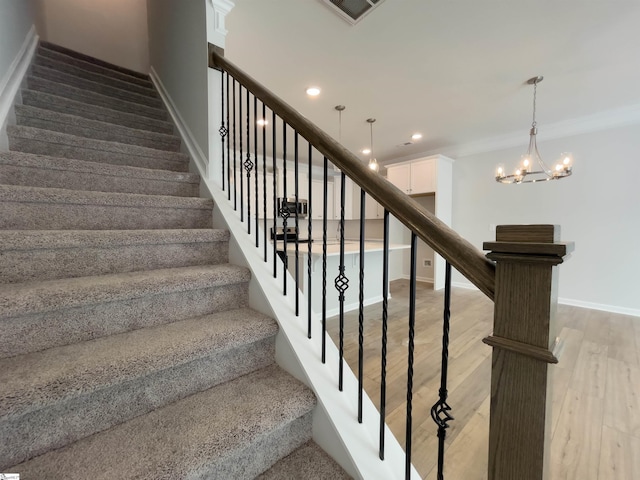 stairway with wood-type flooring, crown molding, and a notable chandelier