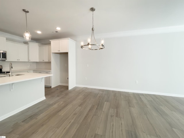 kitchen with decorative light fixtures, a kitchen breakfast bar, white cabinetry, and sink