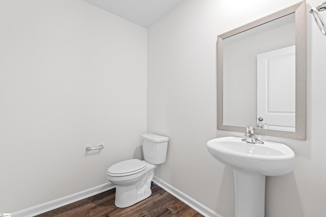 bathroom with a sink, toilet, baseboards, and wood finished floors