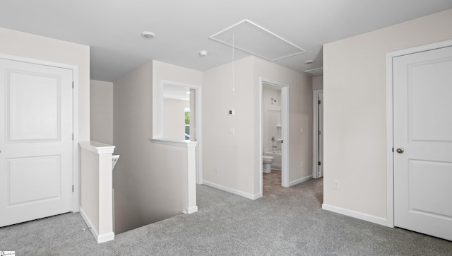 hall featuring carpet flooring, an upstairs landing, attic access, and baseboards