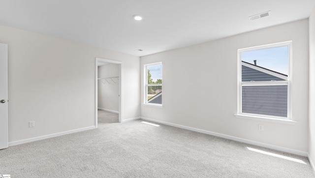 unfurnished bedroom featuring baseboards, visible vents, a spacious closet, carpet flooring, and a closet