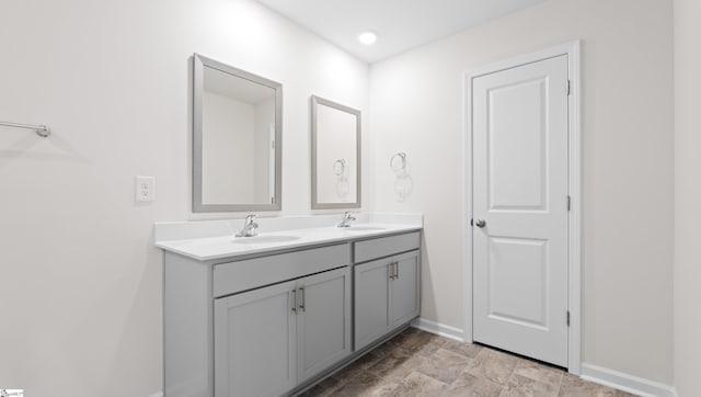 bathroom with double vanity, baseboards, and a sink