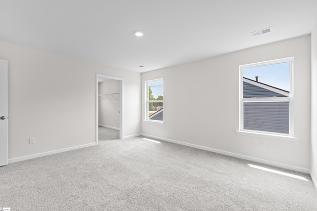 unfurnished bedroom with baseboards, visible vents, a walk in closet, carpet floors, and recessed lighting