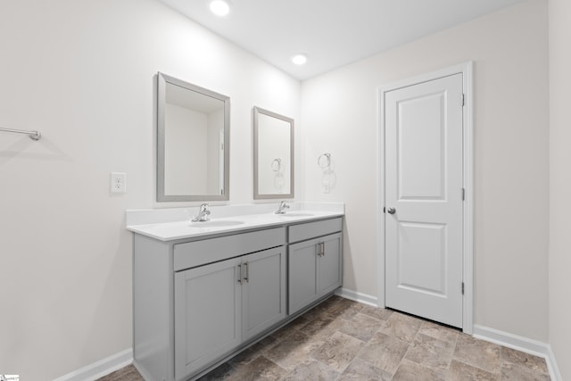 full bathroom featuring double vanity, recessed lighting, a sink, and baseboards