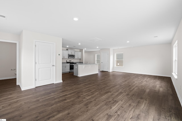 unfurnished living room featuring baseboards, dark wood-style flooring, and recessed lighting