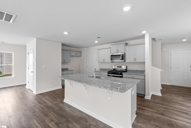 kitchen featuring a sink, visible vents, appliances with stainless steel finishes, dark wood-style floors, and an island with sink