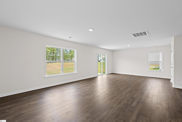 unfurnished room with baseboards, visible vents, and dark wood-style flooring