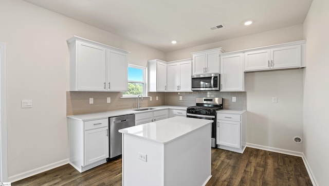 kitchen with white cabinets, sink, dark hardwood / wood-style floors, appliances with stainless steel finishes, and a kitchen island