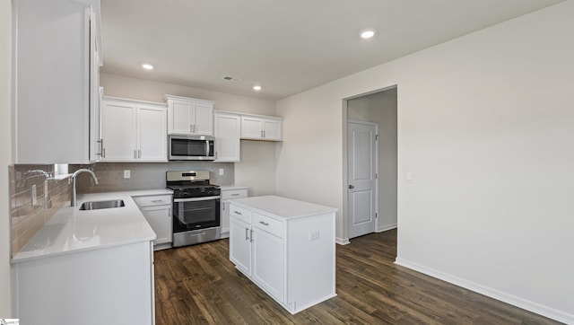 kitchen featuring sink, dark hardwood / wood-style floors, appliances with stainless steel finishes, a kitchen island, and white cabinetry