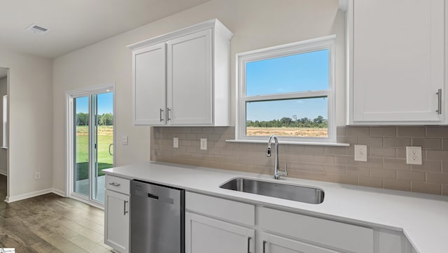 kitchen featuring sink, tasteful backsplash, stainless steel dishwasher, wood-type flooring, and white cabinets