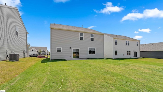 rear view of property with central AC and a lawn