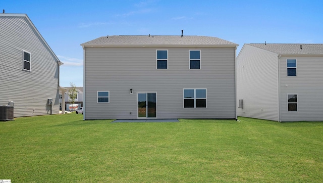 rear view of house with central air condition unit and a yard