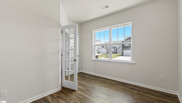 spare room featuring french doors and dark wood-type flooring