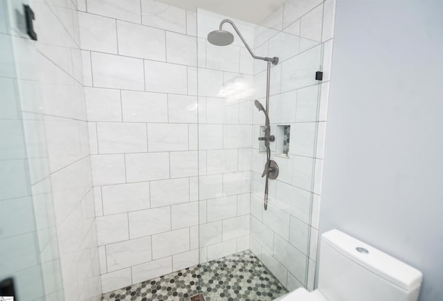 bathroom featuring toilet and a tile shower