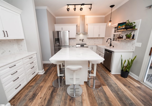 kitchen with stainless steel appliances, white cabinets, a center island, wall chimney range hood, and tasteful backsplash