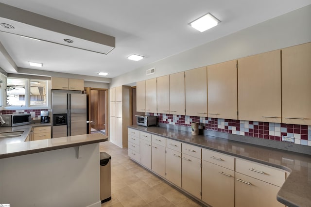 kitchen featuring tasteful backsplash, stainless steel appliances, and light tile floors