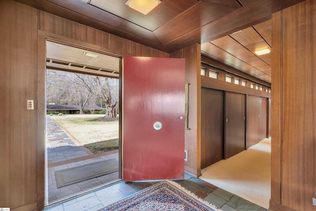 tiled entrance foyer featuring wood walls and wood ceiling