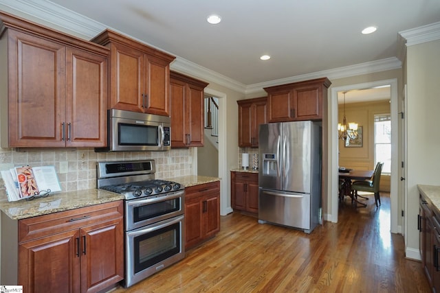 kitchen with an inviting chandelier, light hardwood / wood-style floors, tasteful backsplash, and stainless steel appliances