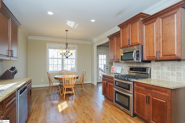 kitchen with backsplash, a notable chandelier, appliances with stainless steel finishes, light hardwood / wood-style flooring, and light stone counters