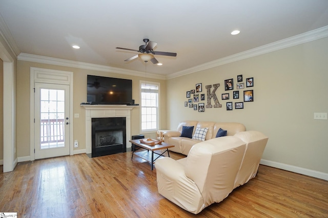 living room featuring ceiling fan, a wealth of natural light, ornamental molding, and light hardwood / wood-style floors