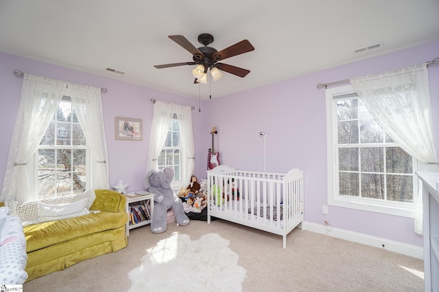 bedroom featuring ceiling fan, light colored carpet, and multiple windows