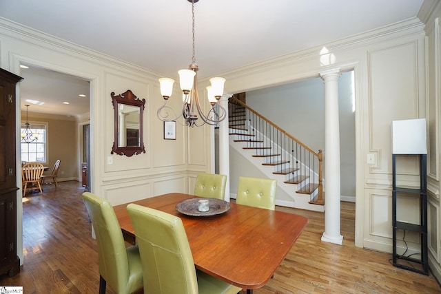 dining space featuring light hardwood / wood-style floors, decorative columns, ornamental molding, and a chandelier