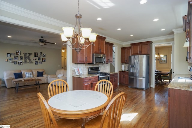 dining space featuring dark hardwood / wood-style floors, ceiling fan with notable chandelier, sink, and ornamental molding